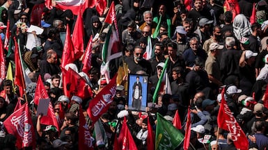 A man raises a portrait of Iran's supreme leader, Ayatollah Mojtaba Khamenei, and his father, Ayatollah Ali Khamenei, as mourners gather for the burial of the former leader of the Islamic Republic. Reuters