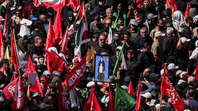 A man raises a portrait of Iran's supreme leader, Ayatollah Mojtaba Khamenei, and his father, Ayatollah Ali Khamenei, as mourners gather for burial of the former leader of the Islamic Republic. Reuters