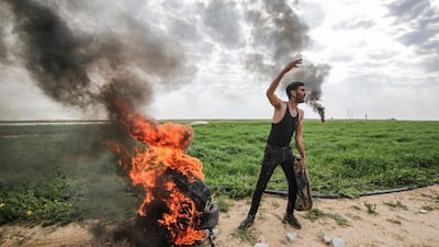 A Palestinian man sets fire to tyres along the Gaza-Israel border east of Khan Yunis in the southern Gaza Strip after Israeli army extracted a body with a bulldozer.