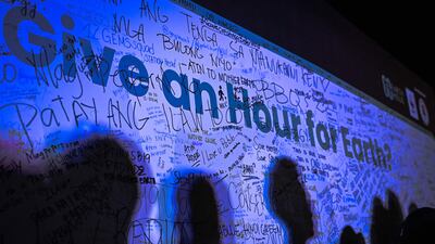 The shadows of people are casted on a wall with the message 'Give an Hour for Earth' at a gathering to mark the Earth Hour environmental campaign in Manila. AFP