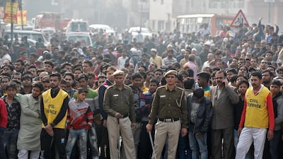 Police stand guard as onlookers gather near the site of a fire that swept through a factory where laborers were sleeping, in New Delhi, India. Reuters