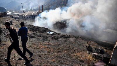 Men look on as a house burns in the village of Charektar outside the town of Kalbajar. Villagers in Nagorno-Karabakh set their houses on fire before fleeing to Armenia. AFP