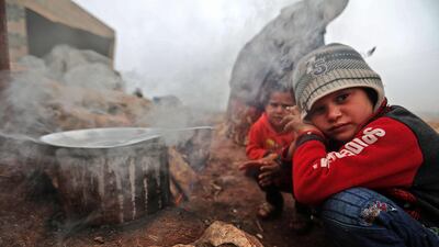 Children warm by the fire in a camp for displaced Syrians near the village of Kafr Uruq, in Syria's northern rebel-held Idlib province. AFP