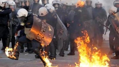 A riot policeman tries to extinguish flames from a petrol bomb thrown by protesters outside the Greek parliament in Athens yesterday. Thousands of protesters gathered in the square outside parliament as politicians debated legislation for unpopular austerity measures that would enable Greece to qualify for a bailout package from the European Union and the International Monetary Fund.