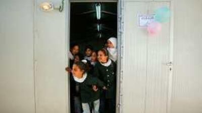 Palestinian students whose school was destroyed during Israel's Gaza offensive in January stand at the entrance of a trailer in Beit Lahiya in the northern Gaza Strip which was donated to Saknain School by Dubai Cares, the UAE-based charity. Suhaib Salem / Reuter