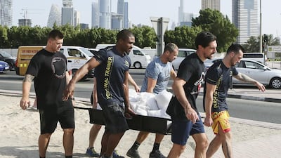 Franky Spencer, third from right, and colleagues attempt a dry run of the stretcher course in Dubai. Competitors say the physical and charity elements are appealing. Sarah Dea /The National