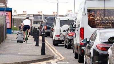 A man cycles with a suitcase past traffic jams in Dover. AP