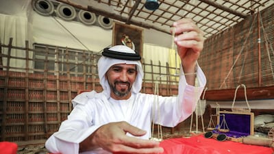 Mohammed Almehairbi, of the Emirates Heritage Club, weighs pearls at the Liwa Date Festival. Victor Besa / The National