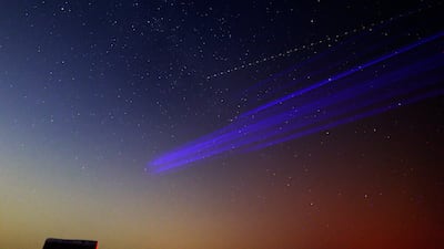 A long-exposure image shows an aircraft (up) flying in the sky as a member of the Dubai Astronomy Group points to where to look prior to the Perseids meteor shower at Al Khatim Desert in Abu Dhabi, United Arab Emirates. Photo: EPA