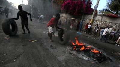 People push tyres near a burning barricade during anti-government protests in Port-au-Prince, Haiti, February 17, 2019. A heavily armed group of foreign nationals were arrested after the protests. Reuters