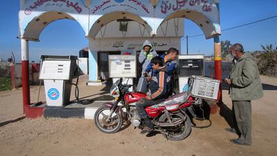 A Palestinian boy fills containers with fuel as he sits on a motorcycle at a petrol station in Khan Younis in the southern Gaza Strip. Ibraheem Abu Mustafa / Reuters
