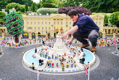 A Legoland Windsor staff member adjusts a model of the Queen Victoria Memorial in front of Buckingham Palace. Legoland's owner is planning to introduce surge pricing at its top attractions. PA