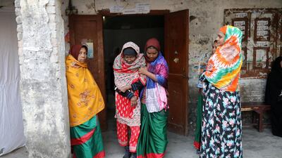 A government official helps an elderly women step out from a voting center in Dhaka. Reuters