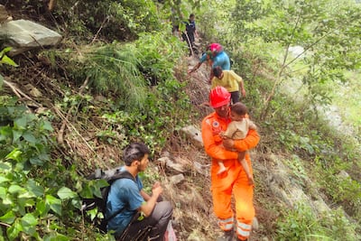 A rescuer helps evacuate stranded pilgrims near a renowned Hindu shrine. AFP