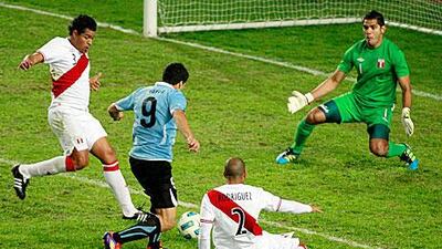 Peru's goalkeeper Raul Fernandez watches as Uruguay's Luis Suarez tries to force his way through.