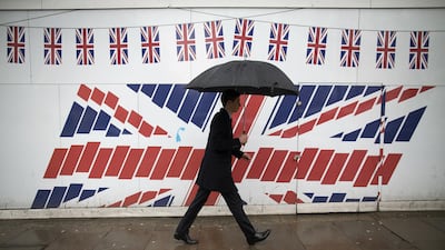 A pedestrian passes construction hoardings decorated with British Union Jack flags in London, UK. Construction PMI rose to 54.7 in November from 53.1 in October. Bloomberg