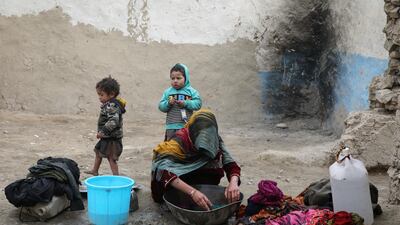 An internally displaced Afghan woman washes clothes outside her shelter on the outskirts of Kabul, Afghanistan February 3, 2021. Reuters