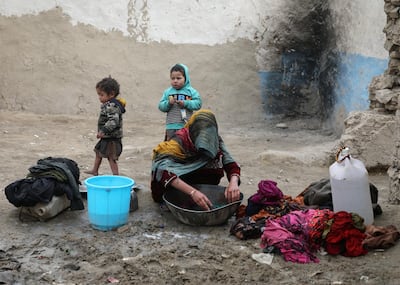 An internally displaced Afghan woman washes clothes outside her shelter on the outskirts of Kabul, Afghanistan February 3, 2021. Reuters