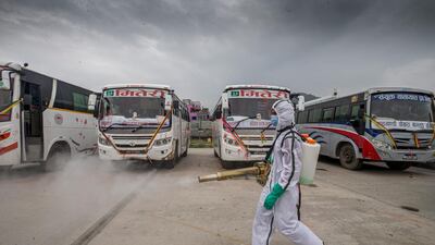 A person in Personal Protective Equipment (PPE) sprays disinfectant on a bus, after the government lifted the restrictions on long distance public transportation, in Kathmandu, Nepal. EPA