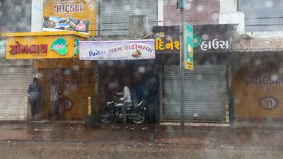 People take shelter from the rain in Mandvi. EPA