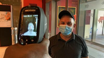 A man, wearing a protective mask to prevent the spread of the coronavirus, has his temperature taken at the Ibn Battuta centre in Dubai. AFP