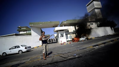 Smoke billows from a burning car as a Libyan rebel stands guard outside the women's military accademy in Tripoli on August 22, 2011. World leaders hailed the rebel takeover of Tripoli, urging Moamer Kadhafi to admit defeat, as Libyans around the world cel???