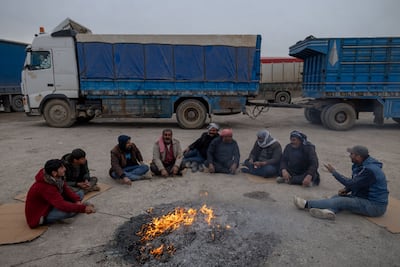 Lorry drivers sit around a fire next to the Iraq-Syria border crossing near the Syrian village of Khanik in Hasakah governorate. Getty Images