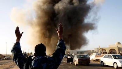 A rebel fighter looks on as government air strikes hit targets in Ras Lanuf.