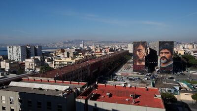 A giant mural of soccer legend Diego Maradona, right, is seen on the side of a building next to another giant mural of a street kid called Niccolò in Naples. AP