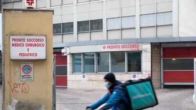 A Deliveroo courier wearing a protective face mask passes Fatebenefratelli Hospital in Milan, Italy, on Tuesday, Feb. 25, 2020. Italy appears never far from a recession, and the spread of the coronavirus may just tip it back into the danger zone. Photographer: Camilla Cerea/Bloomberg
