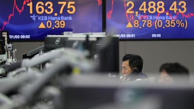 A currency trader talks on the phone near the screens showing the Korea Composite Stock Price Index, right, and the foreign exchange rate at the foreign exchange dealing room in Seoul. (AP Photo/Lee Jin-man)