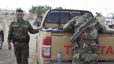 A peshmerga with Kalashnikov looks at supplies in the back of a pickup truck.