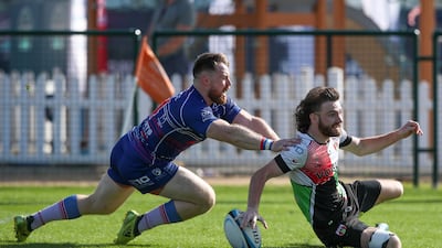James Wilson of Abu Dhabi Harlequins passes Dermot Carr and scores against Jebel Ali Dragons. Victor Besa / The National