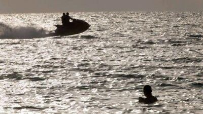 A jet ski passes a bather at a public beach in Dubai.