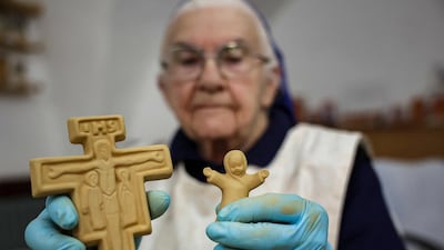 Sister Eliana, a French Catholic nun of the Little Sisters of Jesus, shows clay figurines of a crucifix and child to be sold during the Nativity season. AFP