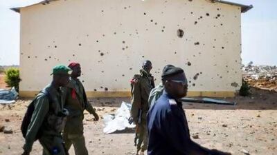 Malian soldiers walk past the bullet ridden wall of a house in a destroyed area of Konna on Saturday. Fred Dufour / AFP