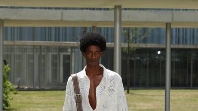 An open cutwork shirt paired with khaki turned-up trousers.