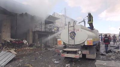 A member of a fire crew sprays water onto a damaged building in a market after an air strike in this screen grab taken from a social media video said to be taken in Idlib, Syria on July 16, 2019. White Helmets