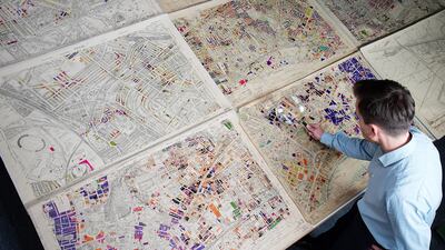 The historic London county council bomb damage maps are viewed through a magnifying glass at the London Metropolitan Archives in London. PA