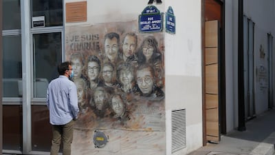 A man wearing a protective face mask as a precaution against the coronavirus looks on a painting by French street artist Christian Guemy, a.k.a. 'C215' in Paris, in tribute to the members of the satirical newspaper Charlie Hebdo attack by jihadist gunmen in January 2015. AP