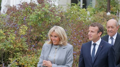 Brigitte, wearing a grey Louis Vuitton dress and coordinated coat, Emmanuel Macron and their dog Nemo, on September 27, 2017. AFP