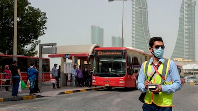 A bus conductor wearing a surgical mask stands in front of a bus station in the Bahraini capital Manama. AFP