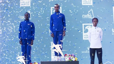 Ababel Yeshaneh, centre, stands atop the podium after smashing her personal best to win the Adnoc Abu Dhabi Marathon. Leslie Pableo for The National