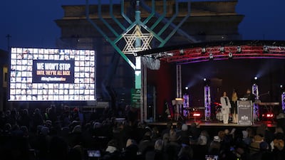 A giant seven-branched candleholder is lit up to celebrate the start of Hanukkah on Thursday in Berlin, Germany, alongside a screen depicting hostages held by Hamas in Gaza. Getty Images