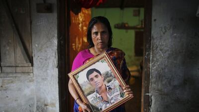 Fatema holds a picture of her son Nurul Karim as she poses for a photograph in front of her slum house in Savar. Fatema lost her son Nurul Karim and her daughter Arifa, who were working on the fifth floor of Rana Plaza when it collapsed on April 24, 2013. Andrew Biraj / Reuters