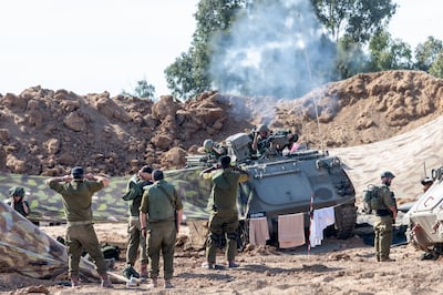 An armoured vehicle fires as soldier's cover their ears on Tuesday in Beeri, Israel. Getty