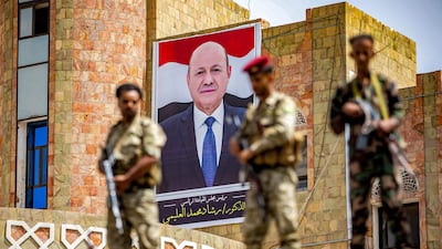 Soldiers loyal to the Aden-based Yemeni government stand guard before a poster showing the chairman of the Presidential Council, Rashad Al Alimi. AFP