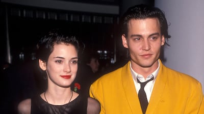 Winona Ryder, in a black dress with opaque sleeves, is joined by Johnny Depp at the 'Cry Baby' premiere on July 1, 1990. Getty