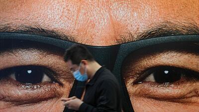 A man wearing a face mask to help curb the spread of the coronavirus walks by an advertisement at a subway station in Beijing. AP