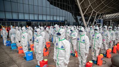 Staff members line up at attention as they prepare to spray disinfectant at Wuhan Railway Station in Wuhan in China's central Hubei province.AFP